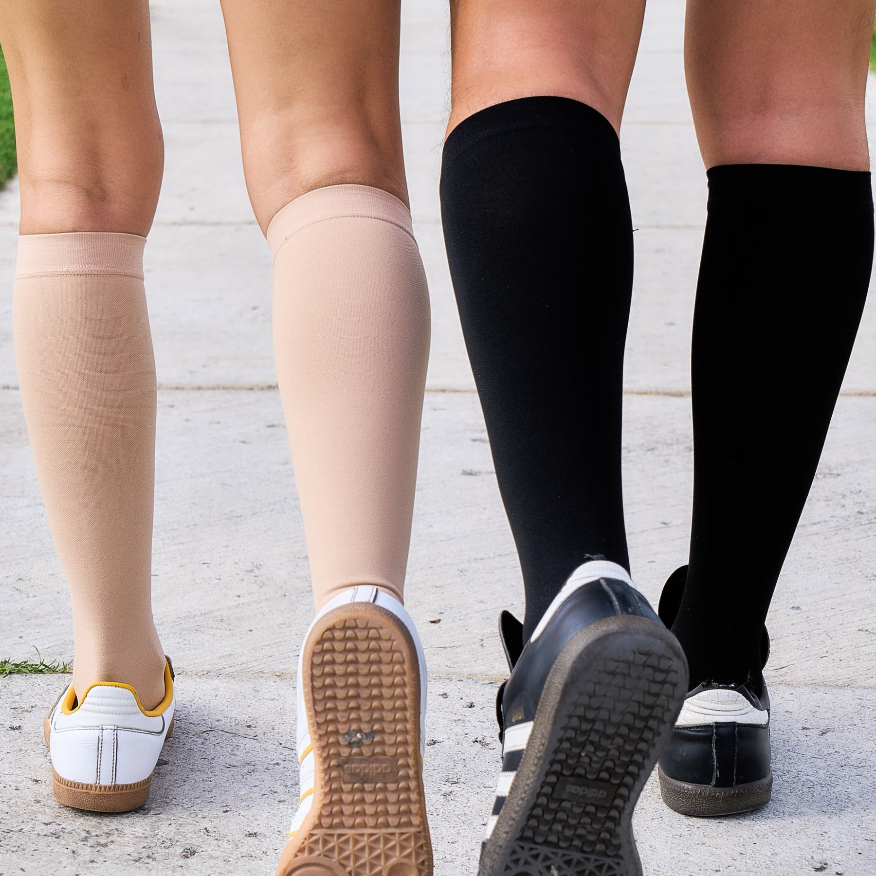two pairs of legs wearing different colored socks on a concrete surface.